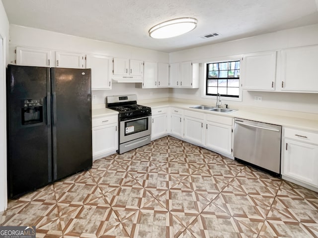 kitchen with sink, appliances with stainless steel finishes, white cabinetry, and a textured ceiling