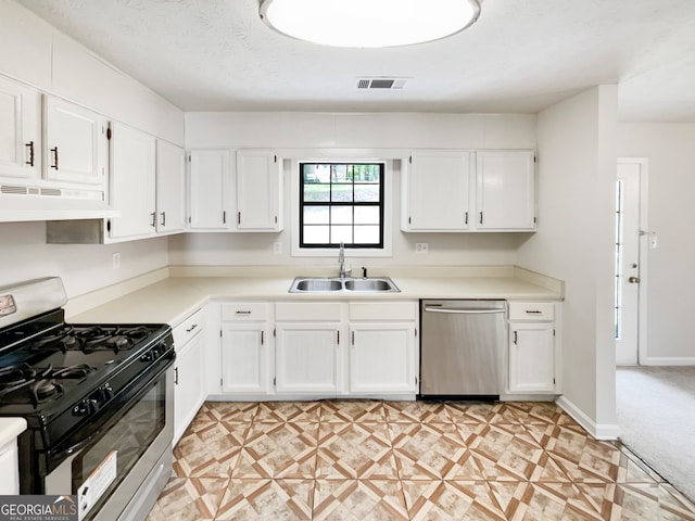 kitchen with appliances with stainless steel finishes, custom exhaust hood, light carpet, sink, and white cabinets