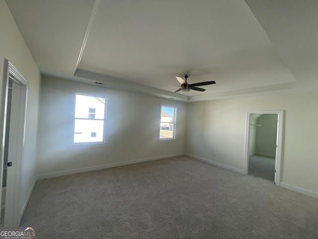 carpeted spare room with a tray ceiling and ceiling fan