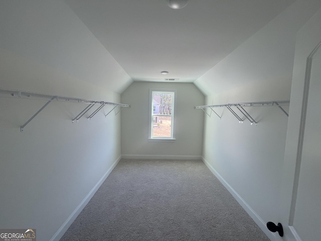 walk in closet featuring light carpet and lofted ceiling