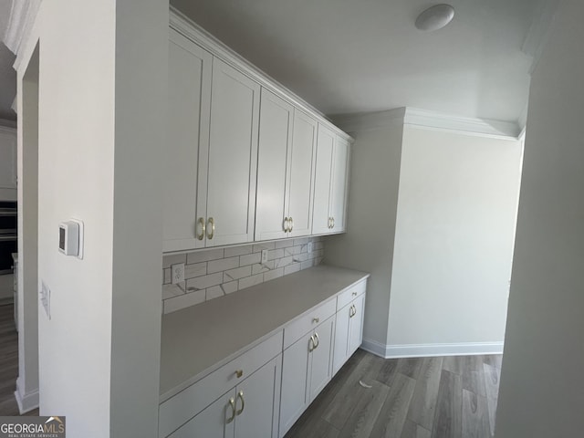 bar with wood-type flooring, tasteful backsplash, and white cabinetry