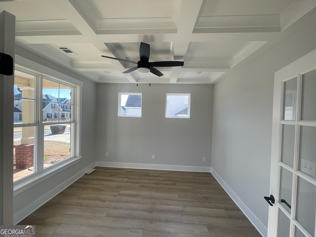 empty room with hardwood / wood-style floors, plenty of natural light, and coffered ceiling