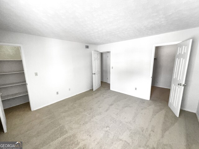 unfurnished bedroom featuring dark carpet and a walk in closet