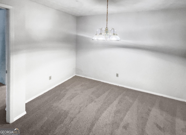 unfurnished room featuring dark carpet and a chandelier