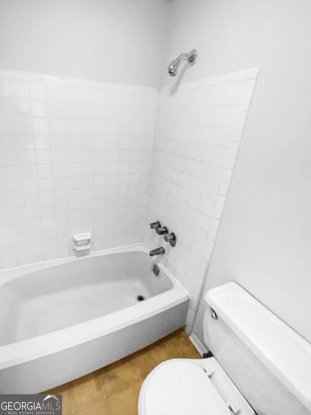 bathroom featuring tiled shower / bath combo, tile floors, and toilet