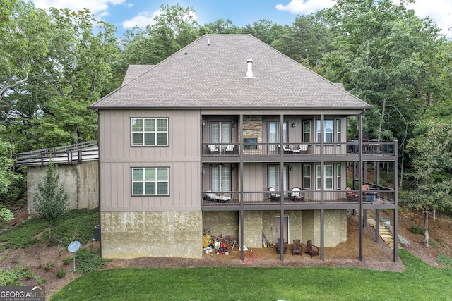 rear view of property with a balcony and a lawn