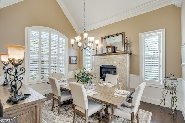 dining area with lofted ceiling, a fireplace, crown molding, and hardwood / wood-style flooring