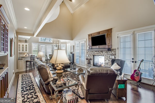 living room with french doors, crown molding, dark hardwood / wood-style flooring, a notable chandelier, and a stone fireplace