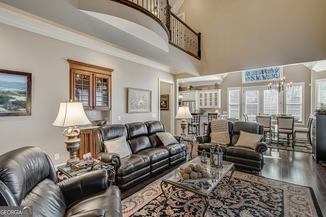 living room with ornamental molding, a notable chandelier, a high ceiling, and dark hardwood / wood-style floors