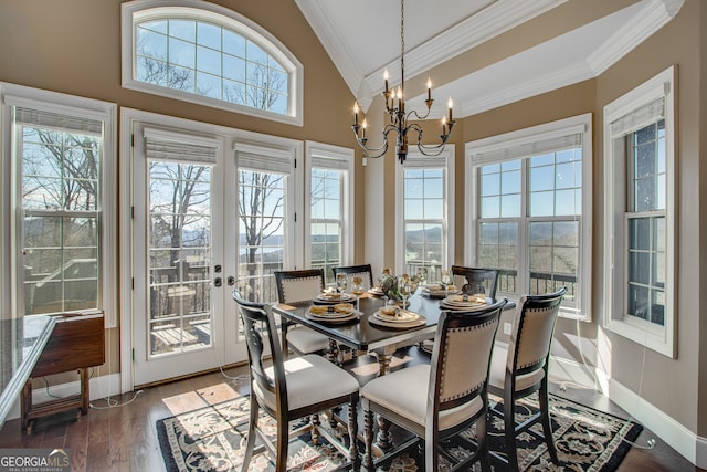 dining space featuring wood-type flooring, lofted ceiling, a notable chandelier, and crown molding