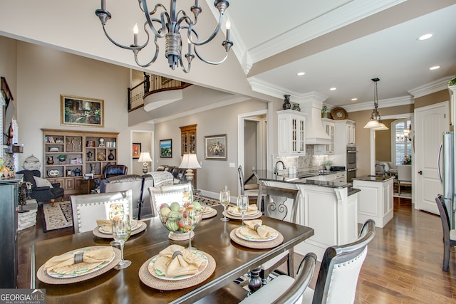 dining room featuring ornamental molding, a notable chandelier, hardwood / wood-style flooring, and sink