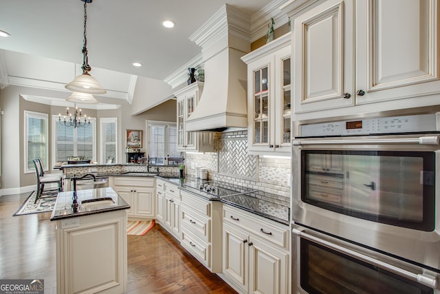 kitchen with wood-type flooring, black electric stovetop, ornamental molding, custom range hood, and stainless steel double oven