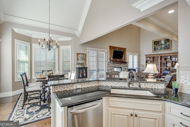 kitchen with a wealth of natural light, dark stone counters, dishwasher, and sink