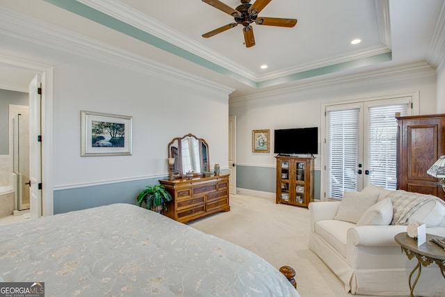 bedroom featuring ceiling fan, ensuite bathroom, a tray ceiling, crown molding, and carpet floors