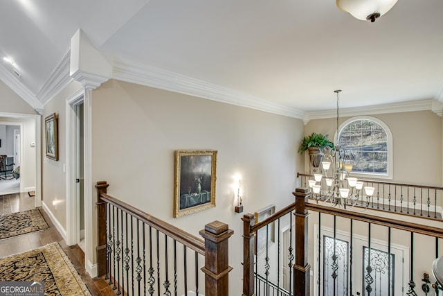 corridor featuring hardwood / wood-style floors, crown molding, and a chandelier