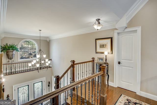 hallway featuring crown molding, hardwood / wood-style flooring, and an inviting chandelier