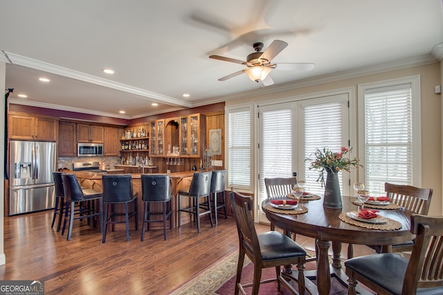 dining space featuring dark hardwood / wood-style flooring, ceiling fan, and crown molding