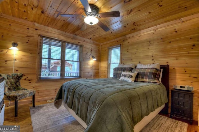 bedroom featuring wooden ceiling, ceiling fan, hardwood / wood-style flooring, and wood walls