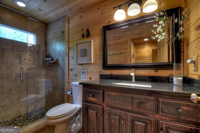 bathroom featuring wooden walls, a shower with door, toilet, and oversized vanity