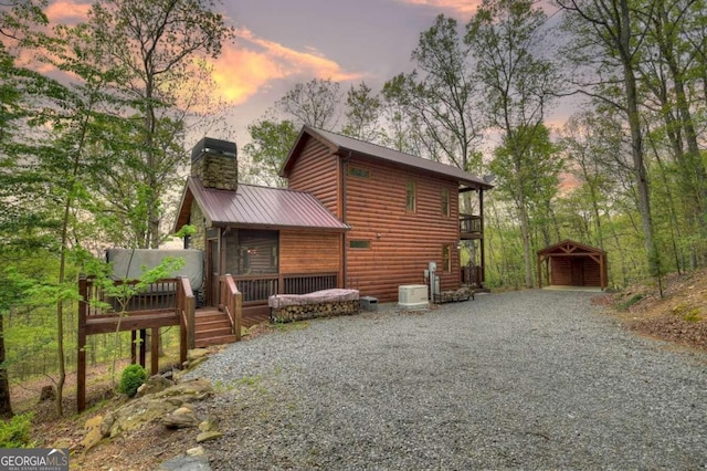 back house at dusk featuring central AC, a wooden deck, and an outdoor structure