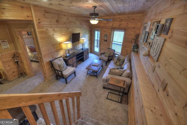 carpeted living room featuring wood walls, ceiling fan, and wooden ceiling