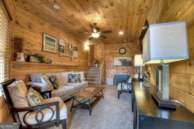 carpeted living room with ceiling fan, wooden walls, and wood ceiling