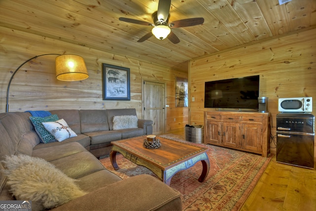 living room with light hardwood / wood-style flooring, ceiling fan, wood walls, and wood ceiling