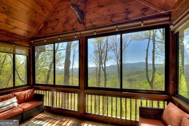 unfurnished sunroom with wooden ceiling, lofted ceiling, and a mountain view