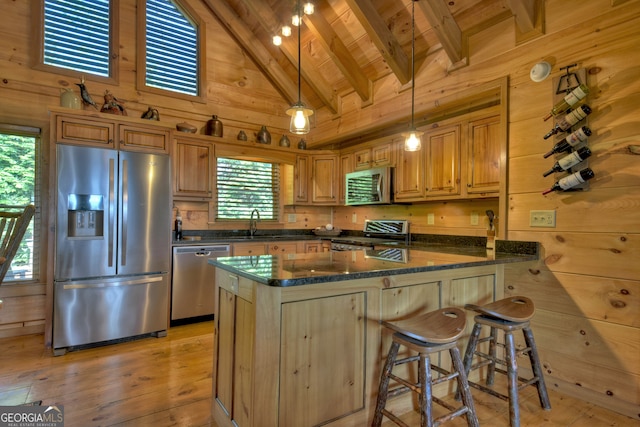 kitchen featuring high vaulted ceiling, wood walls, light wood-type flooring, and stainless steel appliances