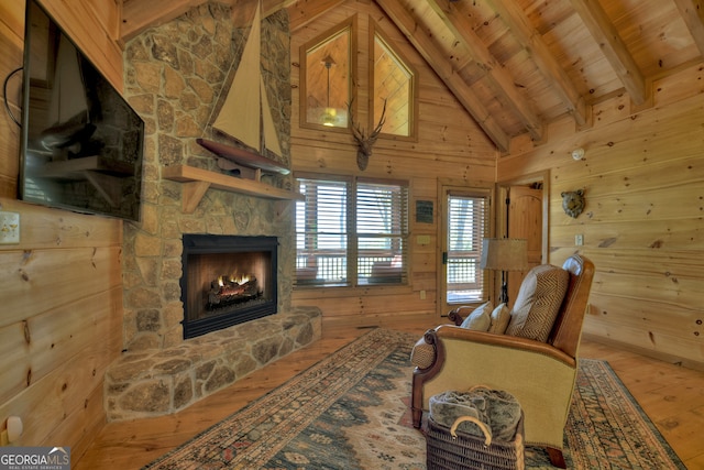 living room with lofted ceiling with beams, wooden walls, wood ceiling, a fireplace, and hardwood / wood-style floors