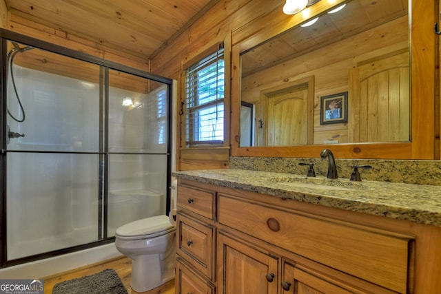 bathroom featuring wood walls, a shower with shower door, vanity with extensive cabinet space, toilet, and wooden ceiling