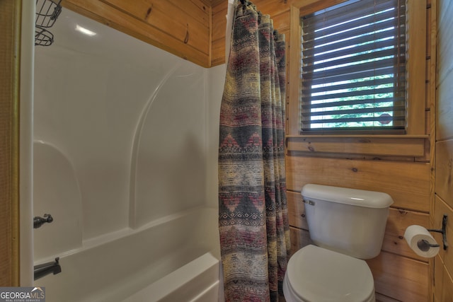 bathroom featuring wooden walls, toilet, and shower / bath combination with curtain