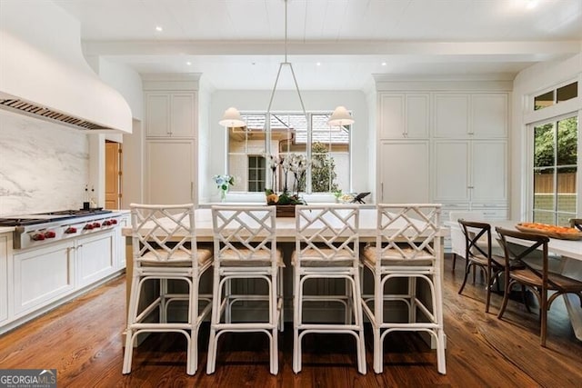 kitchen with custom range hood, hardwood / wood-style floors, a kitchen breakfast bar, and hanging light fixtures