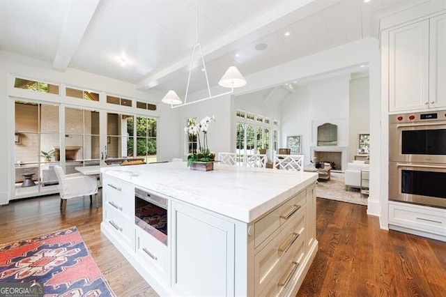 kitchen with lofted ceiling with beams, appliances with stainless steel finishes, a wealth of natural light, and a kitchen island