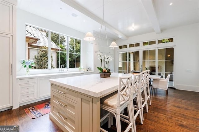 kitchen featuring hanging light fixtures, a center island, dark hardwood / wood-style flooring, beamed ceiling, and a kitchen breakfast bar