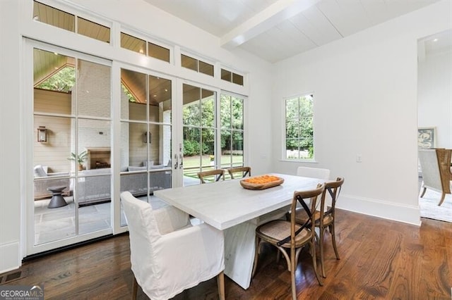 dining room featuring a large fireplace, a wealth of natural light, dark hardwood / wood-style floors, and lofted ceiling with beams