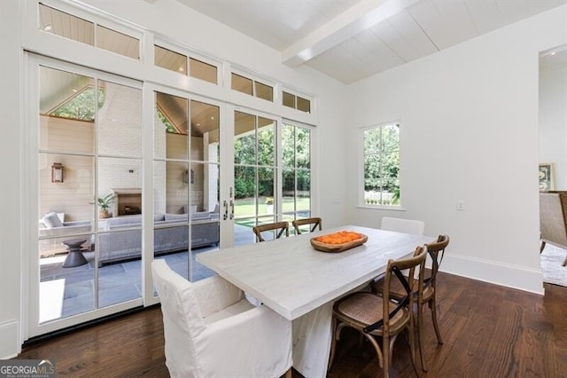 dining area featuring dark wood-type flooring, a large fireplace, and lofted ceiling with beams