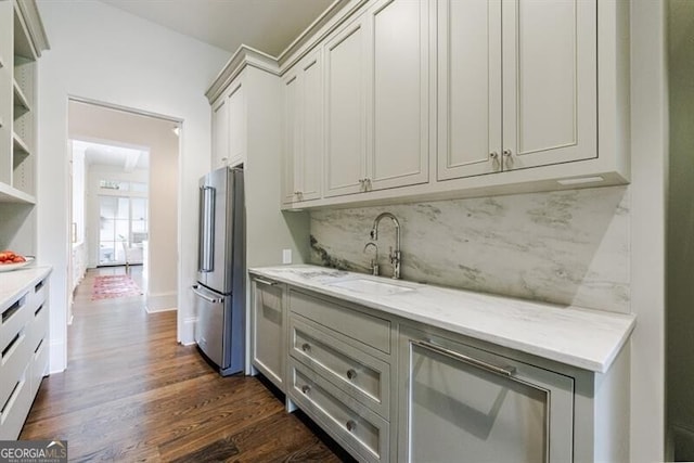 kitchen with stainless steel fridge, dark wood-type flooring, sink, decorative backsplash, and light stone counters