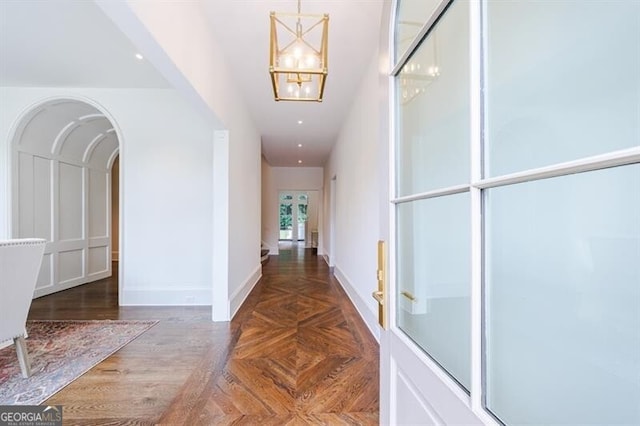 hall featuring parquet floors and a notable chandelier