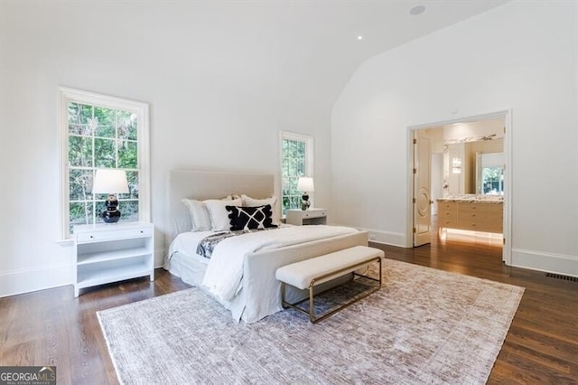 bedroom with lofted ceiling, connected bathroom, and dark hardwood / wood-style floors