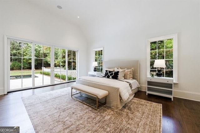 bedroom with dark wood-type flooring, multiple windows, high vaulted ceiling, and access to exterior