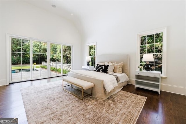 bedroom featuring access to exterior, dark hardwood / wood-style flooring, high vaulted ceiling, and multiple windows