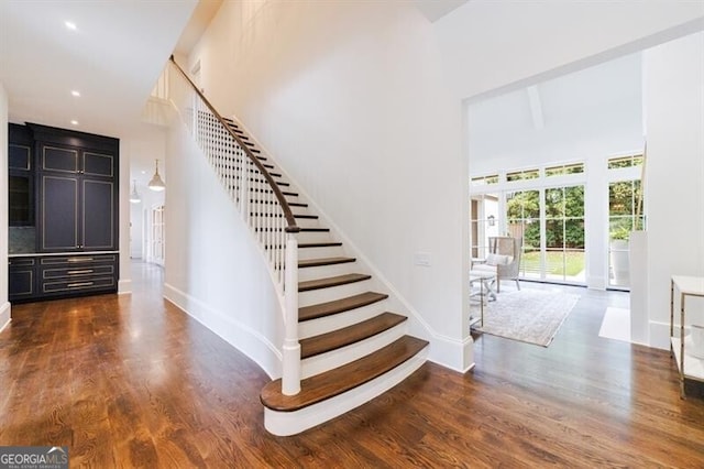 stairs featuring a towering ceiling and hardwood / wood-style floors