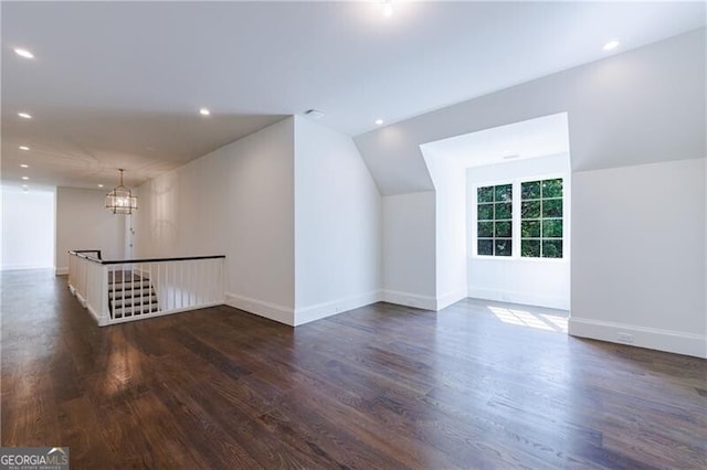 bonus room featuring vaulted ceiling, dark hardwood / wood-style flooring, and an inviting chandelier