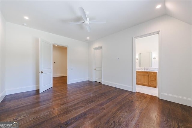 unfurnished bedroom featuring lofted ceiling, dark wood-type flooring, ceiling fan, and connected bathroom