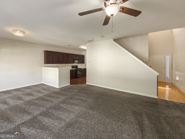 unfurnished living room with ceiling fan and dark colored carpet