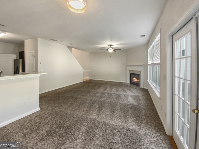 unfurnished living room with ceiling fan and dark carpet