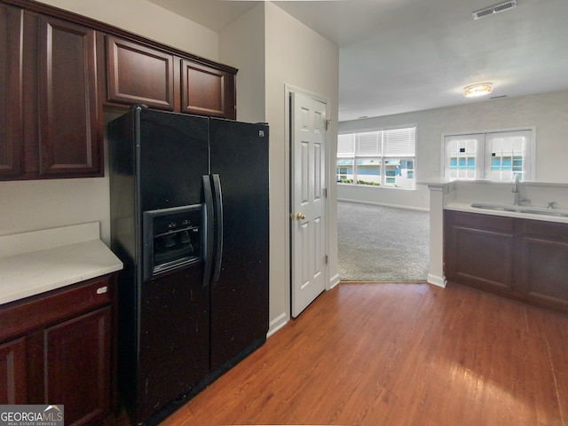 kitchen featuring light hardwood / wood-style flooring, sink, black fridge with ice dispenser, and dark brown cabinets