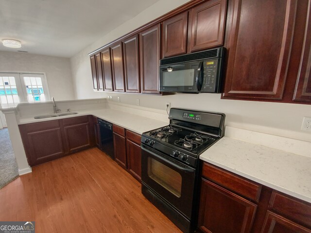 kitchen featuring kitchen peninsula, light hardwood / wood-style flooring, black appliances, and sink