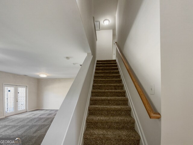 stairs featuring french doors and dark carpet